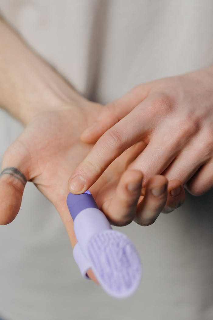 A detailed view of a purple finger vibrator being held and used for massage.