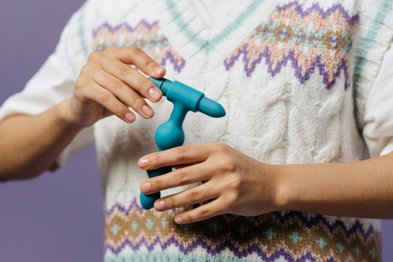 Intimate close-up of hands holding a blue personal massager, featuring detailed texture and modern design.