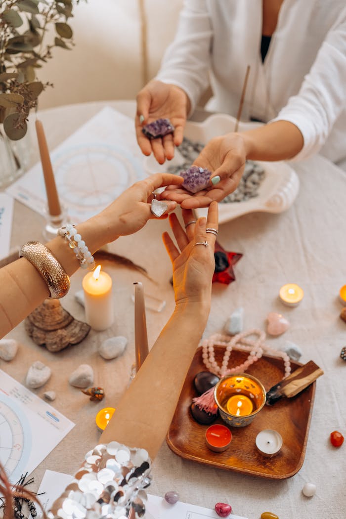 A serene indoor setting with hands exchanging healing crystals, surrounded by candles and spiritual items.